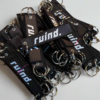 A pile of 'Ruind' jet tags, showcasing the bold front logo.  Perfect for adding a unique touch to keys or accessories.